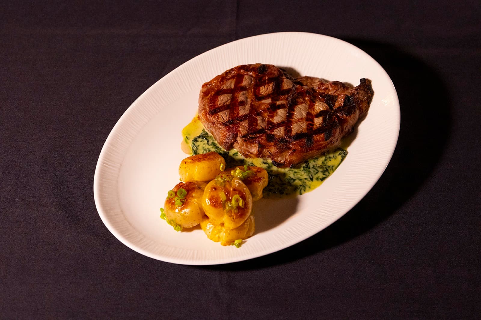 Chargrilled 14oz ribeye over creamed spinach with glazed potatoes